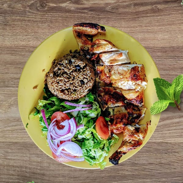 Riva's Bbq Restaurant's grilled chicken with rice, beans, and a fresh salad on a yellow plate.
